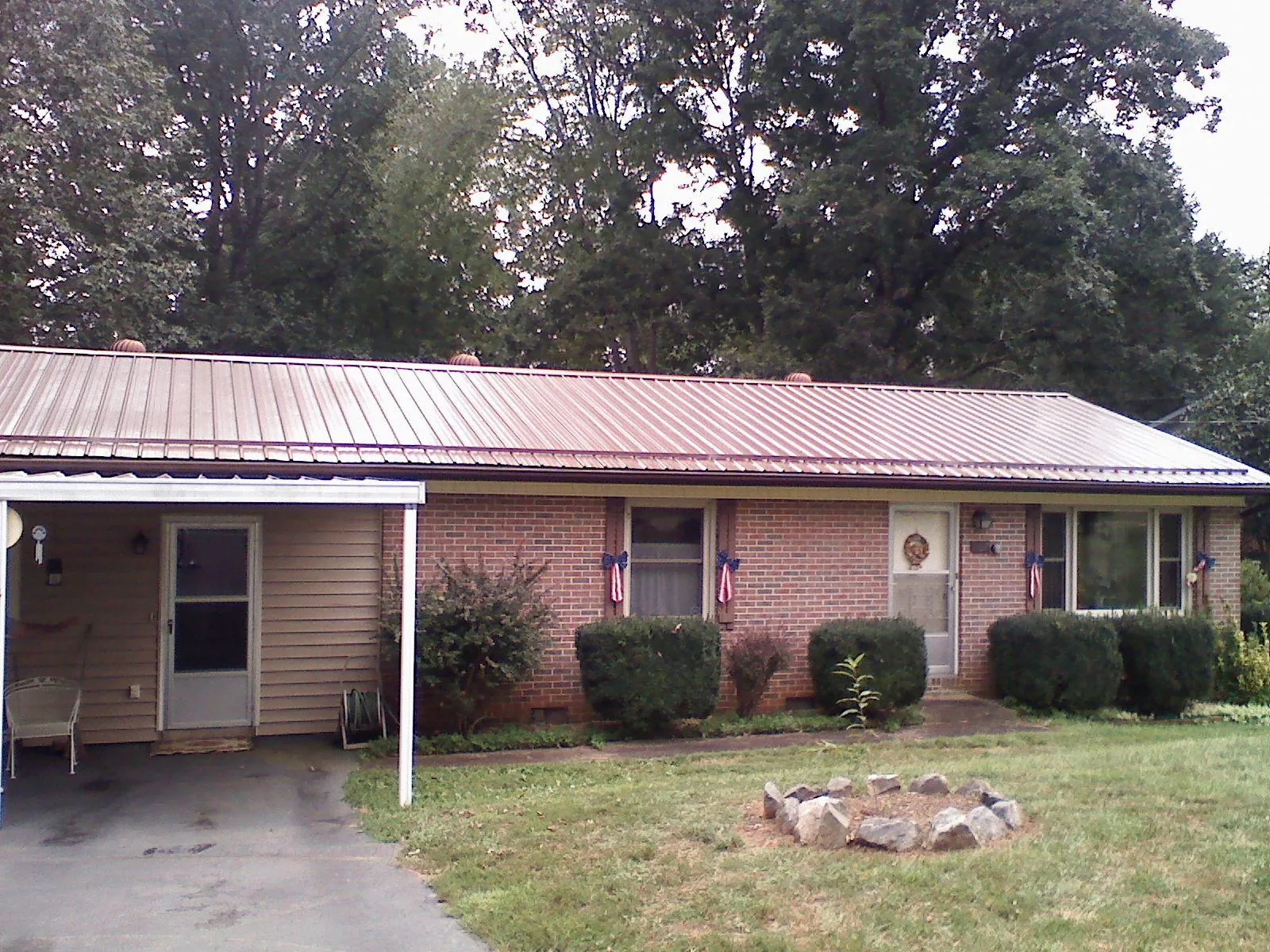 Bronze metal roof and carport on a brick ranch home — Roof Repair work by our crew in Jefferson City